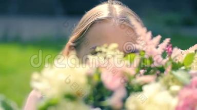 年轻的女演员对着镜头凝视着，透过花的装饰，在绿色神奇的草地花园课程中